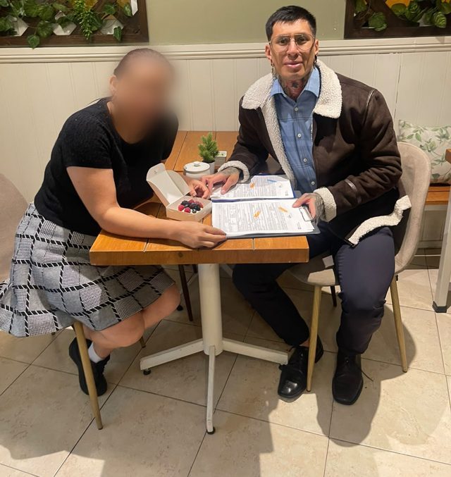 Clienta y Carlos revisando su solicitud en una cafetería, rostro de la clienta difuminado